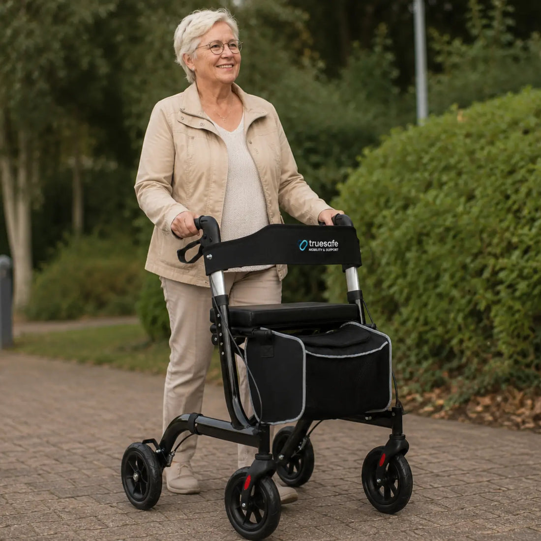 Oudere vrouw wandelt zelfstandig met de zwarte TrueSafe lichtgewicht opvouwbare rollator in een park. Geschikt voor veilig gebruik binnen en buiten.